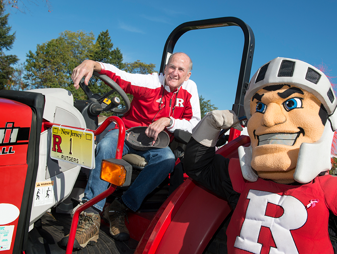 President Barchi sitting on a tractor with the Scarlet Knight at the 2017 Fall Family Festival